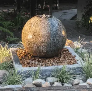 A large stone water feature in the middle of a garden.