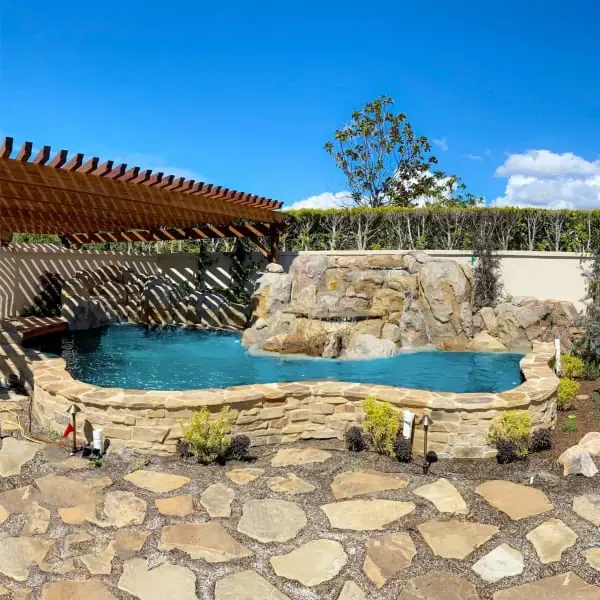A backyard with a pool and a stone patio.