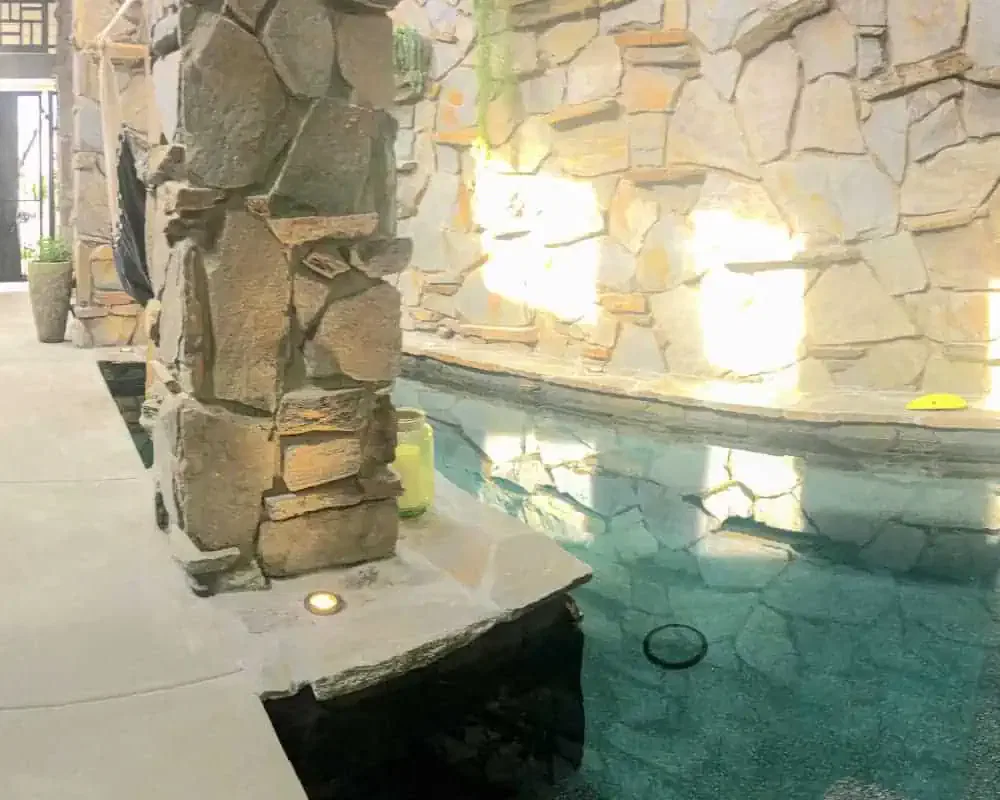 A pool with a stone wall and pillars.