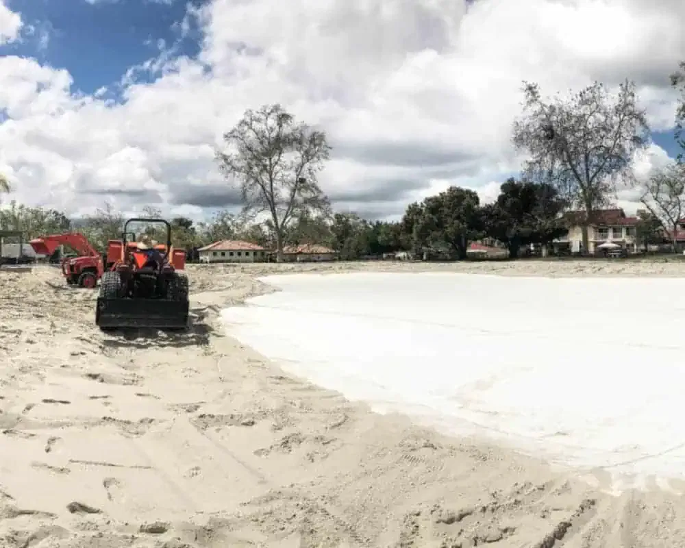 A sand dune is being constructed on a beach.