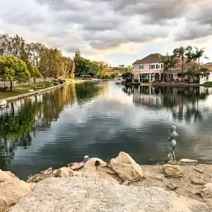 A lake with a boat and houses in the background.