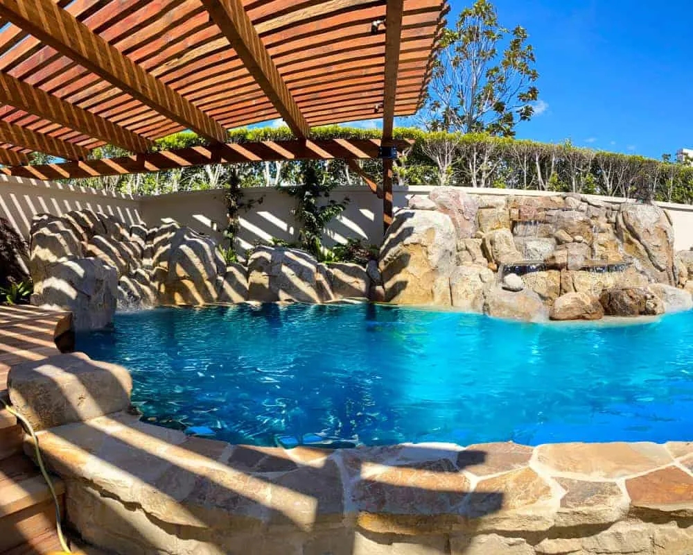 A swimming pool in a backyard with a wooden deck.