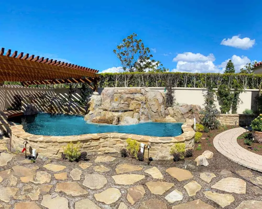 A backyard with a stone patio and a pool.