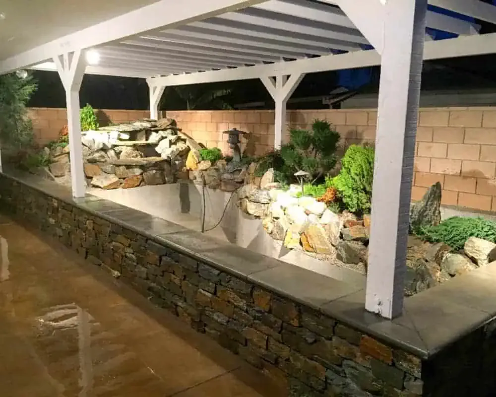 A stone asian theme above ground koi pond with asian and plants.