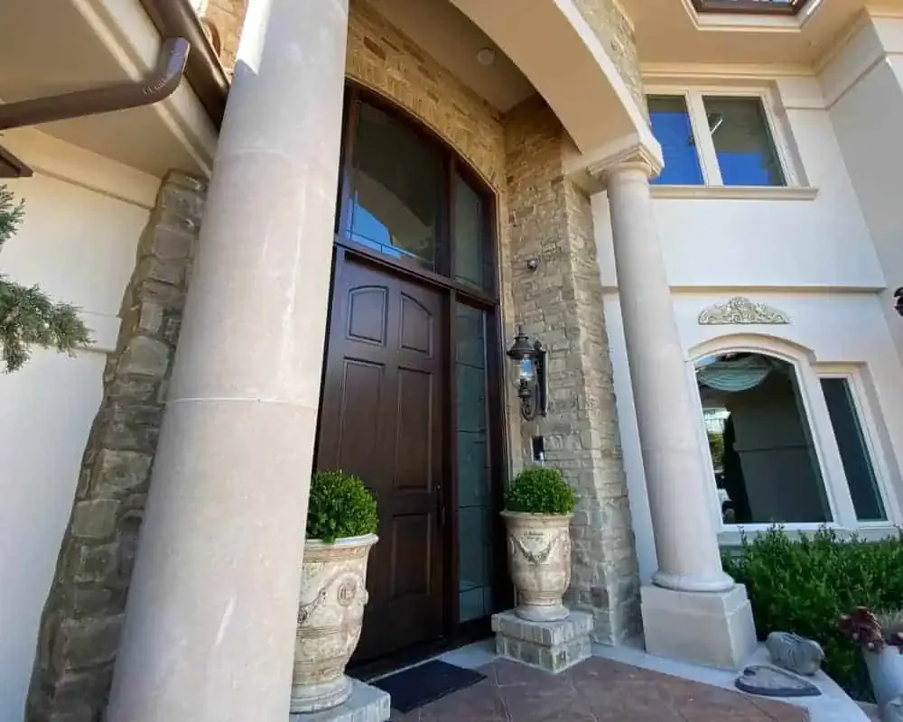 A front entrance to a home with columns and potted plants.