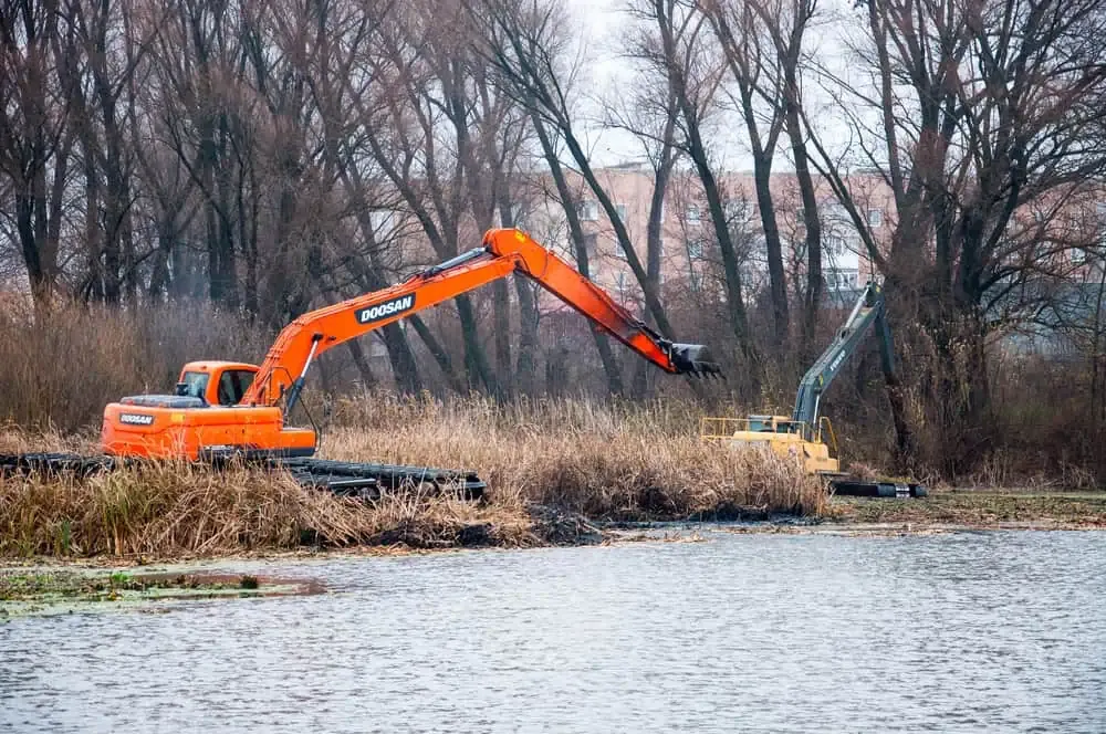 An excavator is dredging in the pond.