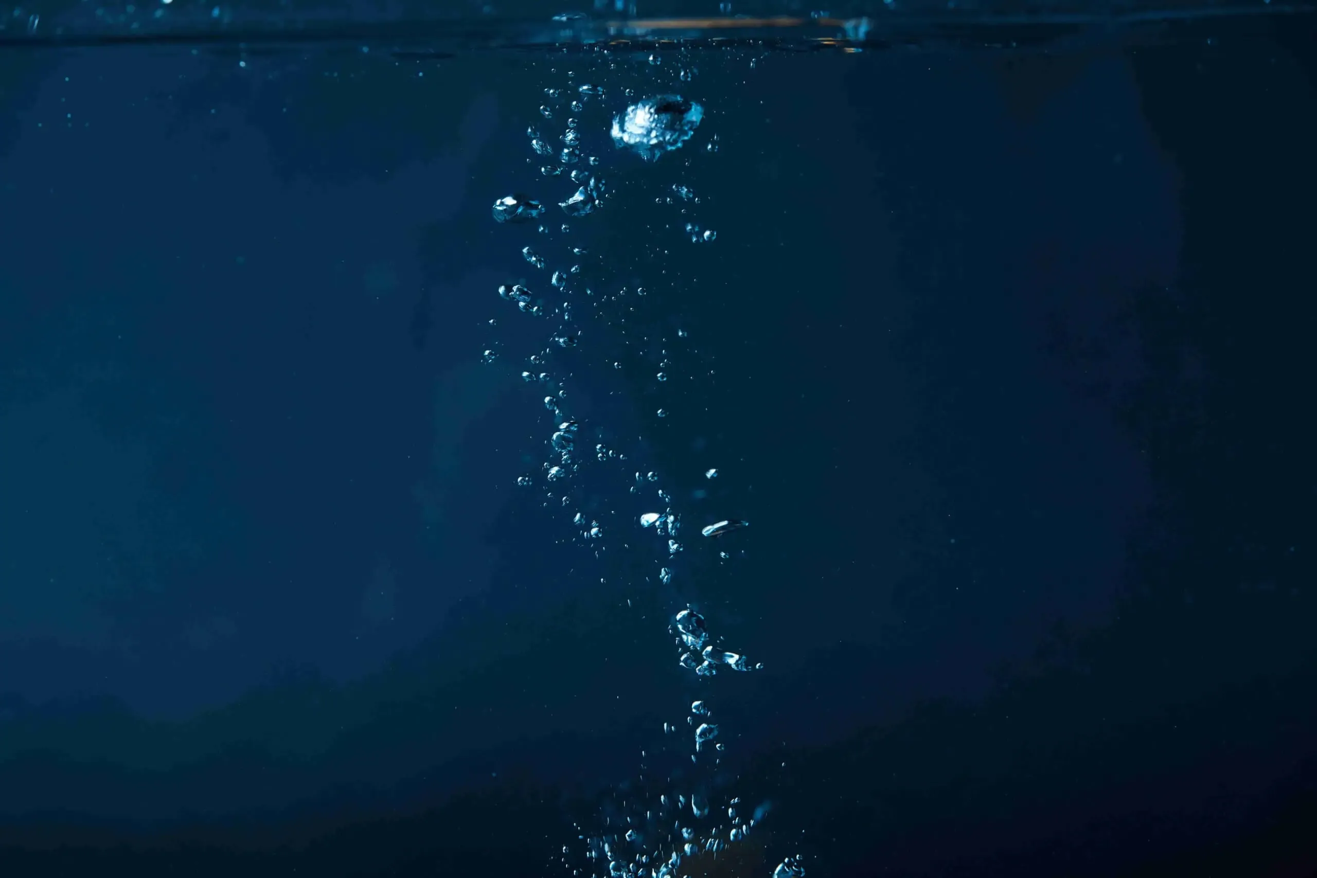 Bubbles rising in dark blue water against a deep blue background, reflecting pristine water quality.