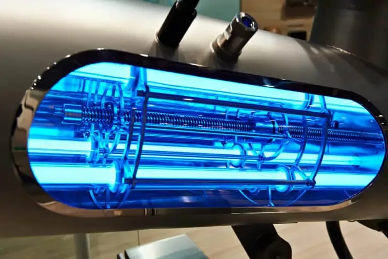 Close-up view of a modern industrial UV light disinfection system, an essential pond and lake tool, featuring blue glowing tubes and metal components.