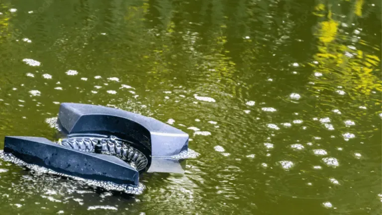 A broken piece of machinery is partially submerged in a murky, foamy body of water, surrounded by floating skimmers attempting to clear the debris.